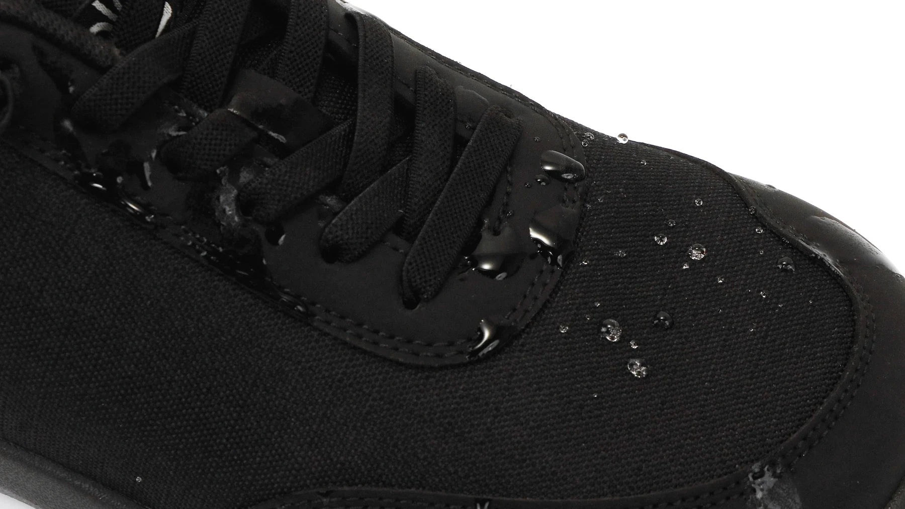 Water beads on the ripstop-nylon upper of a black Footle Water-Resistant shoe